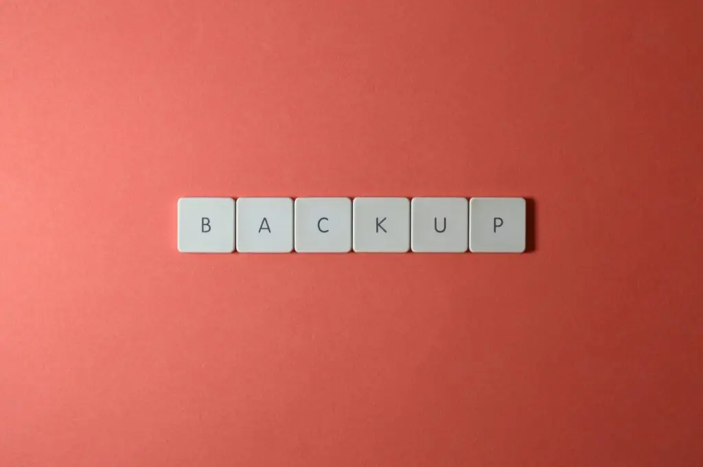 Free Close-up of keyboard keys spelling 'BACKUP' placed on a coral-colored surface. Stock Photo